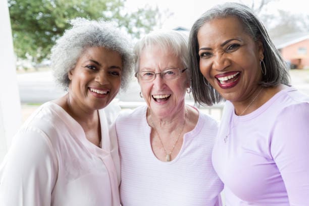 Three Older Women Smiling Joyfully While Posing Together for a Photograph.