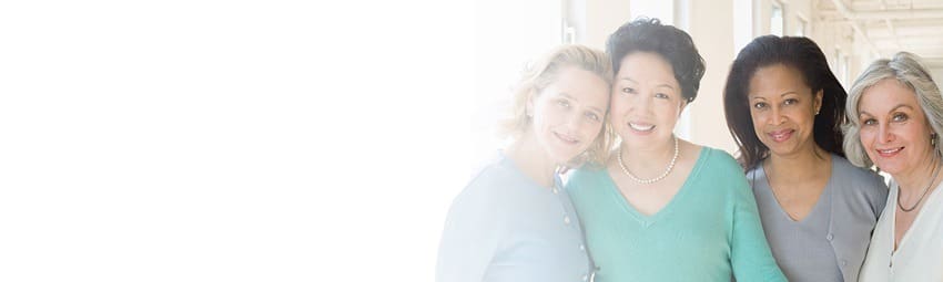 A Group of Women Standing Together in a Hallway, Engaged in Conversation and Sharing Smiles.
